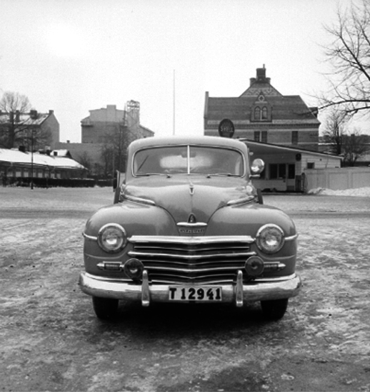 Taxi.
Stenström. 
Taxin står på Trädgårdsgatan. Till höger Stortorget och macken som låg i hörnet Trädgårdsgatan/Stortorget där senare gamla polishuset byggdes. Bensinmacken sålde bensinmärket Shell. I fonden till höger syns norra delen av Nikolaiskolan. 
Till vänster Oskarsparken och f.d. Köttbesiktningsbyrån, den låga byggnaden. 
Bilen är en amerikansk Plymouth från 1946 till 1948.
