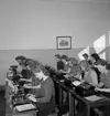 Klassrumsinteriör, flickgrupp, maskinskrivning.
P.M.