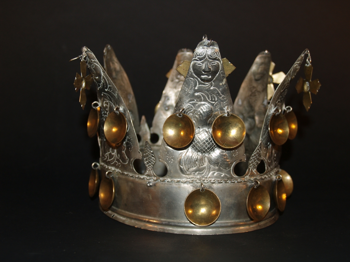 Det er ei heilrend krone, det vil seie at den er klipt/sagd ut av ei metallplate og lodda saman. Den har seks taggar og er ei open krone. Kvar tagg er dekorerte med blomemønster og i toppen er det eit ansikt, som kan tolkast som annankvar mann og kvinne. I kvar tagg er det eit heng med eit kors i messing, det er også to blad i messing halvvegs opp på kvar tagg og 12 messingblad langs med ein bøljekant nede. Under blada er det ein glatt kant utan dekor, den glatte kanten avsluttast i to bølgjer. Denne glatte kanten er vanleg på kroner og her skal det vere eit band eller eit tøystykke. I ein avisartikkelen i avisa Samhold frå 1954 er krona vår avbilda med eit tøystykke rundt, og i tilvekstprotokollen er det ført inn at krona har eit raudt fløyelsband. Dette er seinare strøket over og tøystykket er dessverre borte.