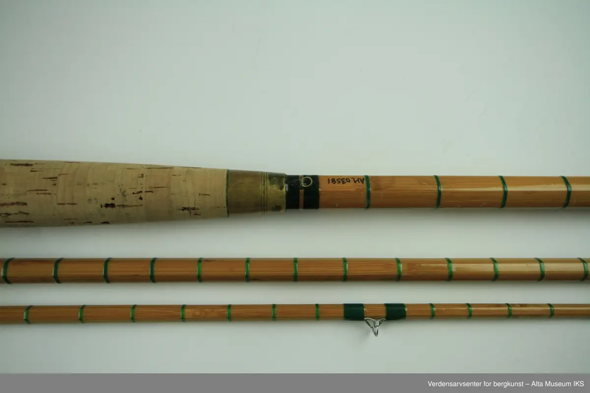 Tohånds fluestang. Tredelt. Tungbygd splitcane med stålkjerne. klasse # 11-12. Skruholker (kom etter knyteholkene) av messing. Sliding ring snellefeste. Har vært brukket i toppen mellom andre og tredje ring. Nye grønne surringer. Endebutt i messing og gummi.