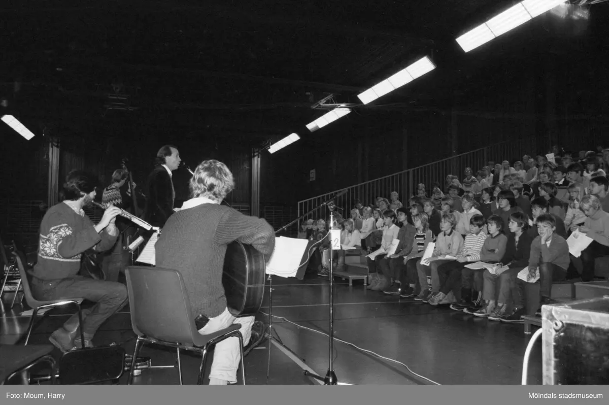 Trubaduren och viskompositören Alf Hambe håller tillsammans med gruppen Vindharpan konsert i Ekenskolans gymnastiksal i Kållered, år 1983.

För mer information om bilden se under tilläggsinformation.