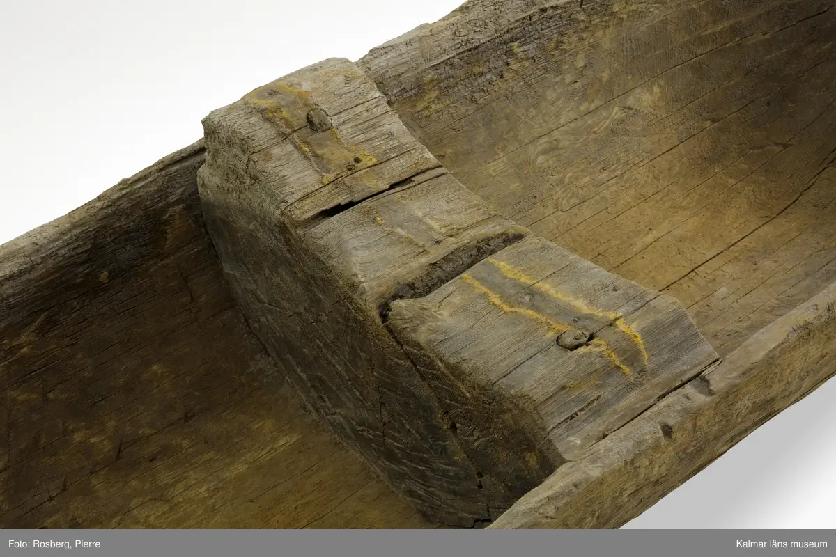 KLM 9352. Båt, stockbåt. Av stor urholkad trädstam, troligen furu. Huggen i ett stycke. Stamrunt tvärsnitt med runt, fallande överhäng. Två tofter och i mitten ett fotstöd. Går ej att uskilja för och akter. Rektangulära och rakt avskurna stävnockar, på den ena ett tamphål.