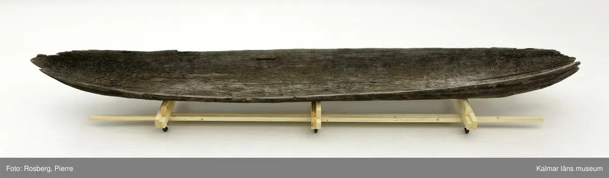 KLM 45161. Båt, stockbåt. Av stor urholkad trädstam. Huggen i ett stycke. Stamrunt tvärsnitt. Går ej att urskilja för repektive akter. Har troligen varit mer rundad i formen, nu sprucken och utvikt. Båten är nästan svart i färgen, eventuellt tjärad.