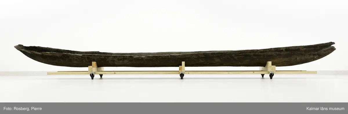 KLM 45161. Båt, stockbåt. Av stor urholkad trädstam. Huggen i ett stycke. Stamrunt tvärsnitt. Går ej att urskilja för repektive akter. Har troligen varit mer rundad i formen, nu sprucken och utvikt. Båten är nästan svart i färgen, eventuellt tjärad.