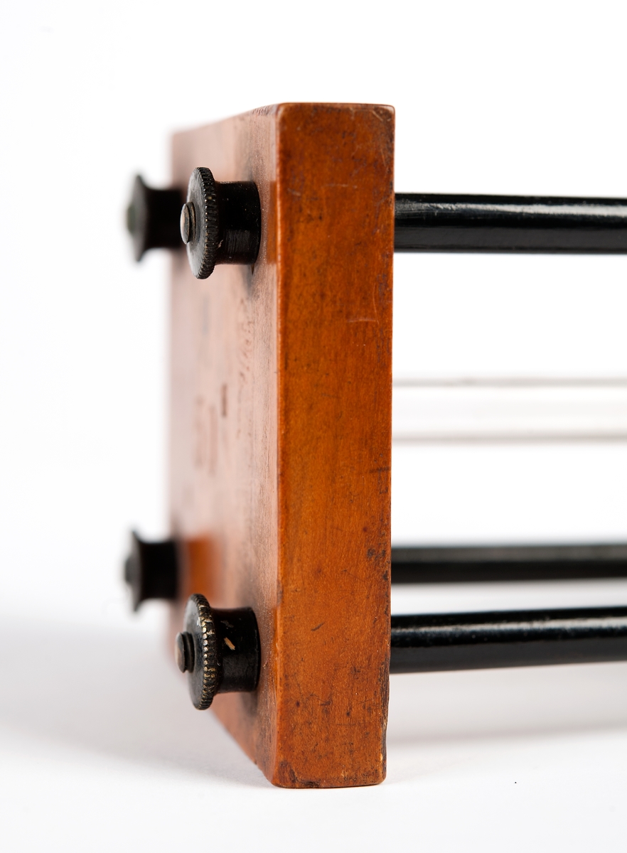 30 sek, rörformat, uppeburet av stativ med 4 metallpelare på 24-kantig mahognyplan.