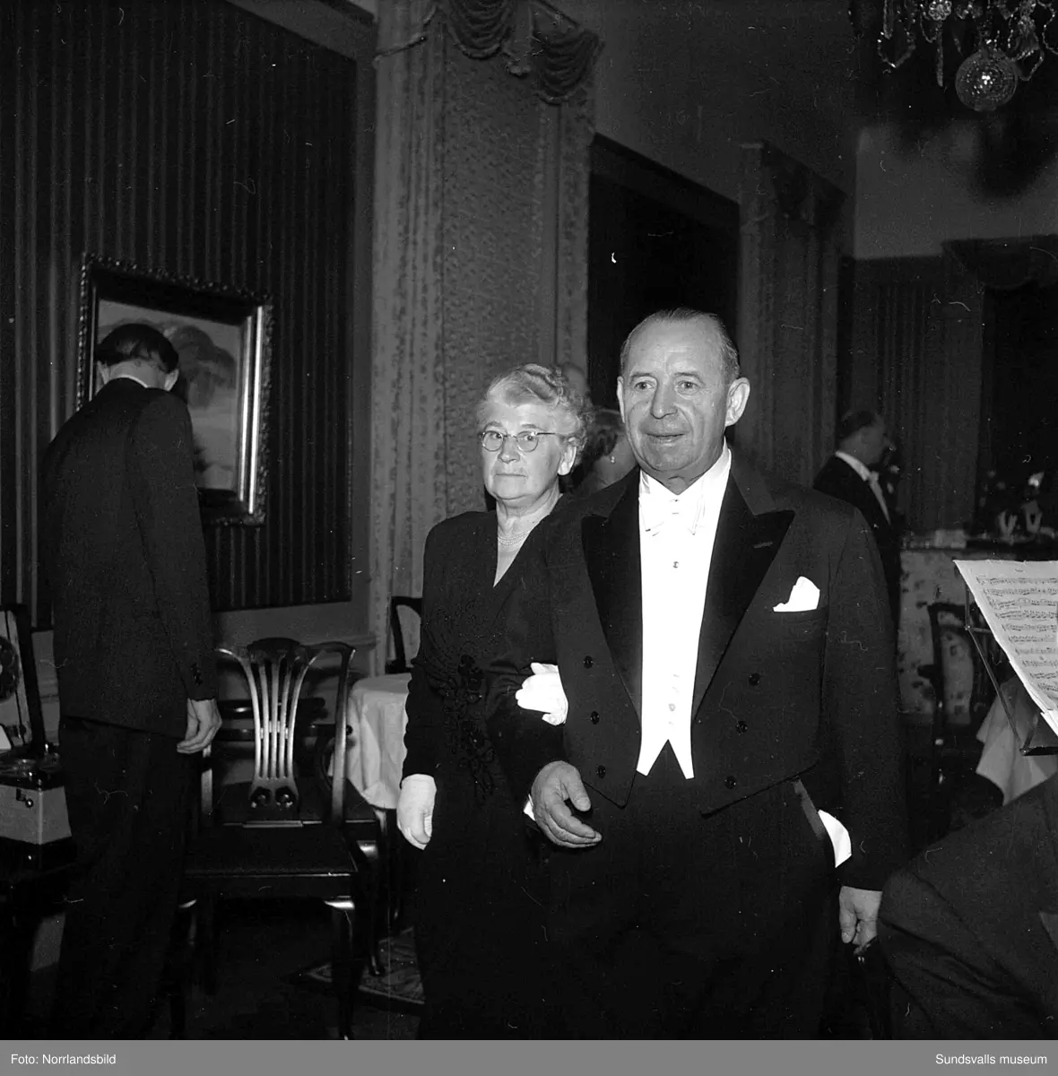 Ett urval av en stor grupp bilder från Lindgrens järnhandels 100-årsjubileumsfest på Knaust. Storstilad entré, mingel, utmärkelser, galamiddag och dans. Underhållning av bland annat en mycket ung Ingeborg Nyberg. På bilderna syns bland annat direktör Fridolf Brunnzell och lagerchefen Carl "Spiken" Lundberg, vilken samma år firade 50 år som anställd vid företaget.