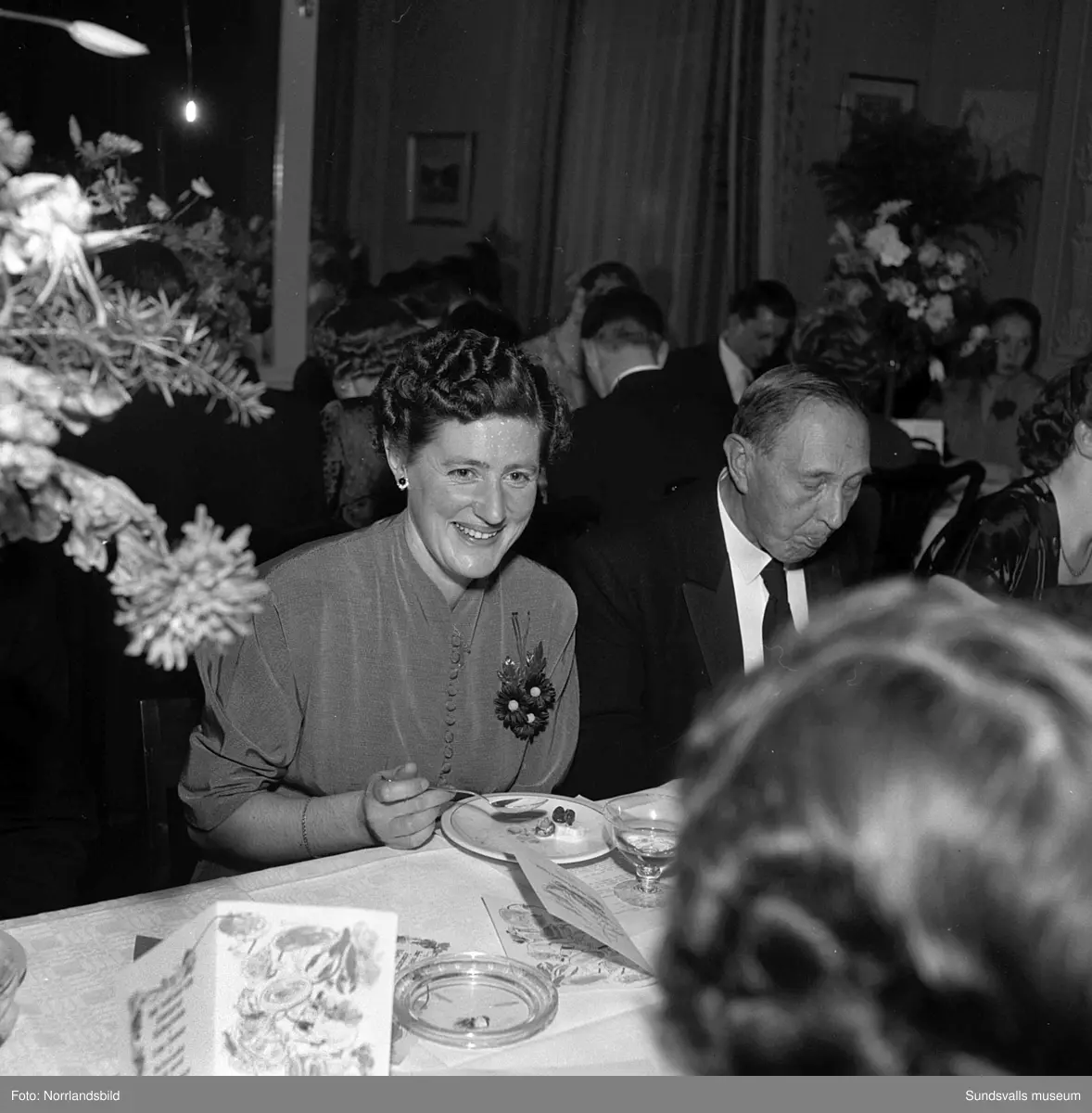 Ett urval av en stor grupp bilder från Lindgrens järnhandels 100-årsjubileumsfest på Knaust. Storstilad entré, mingel, utmärkelser, galamiddag och dans. Underhållning av bland annat en mycket ung Ingeborg Nyberg. På bilderna syns bland annat direktör Fridolf Brunnzell och lagerchefen Carl "Spiken" Lundberg, vilken samma år firade 50 år som anställd vid företaget.