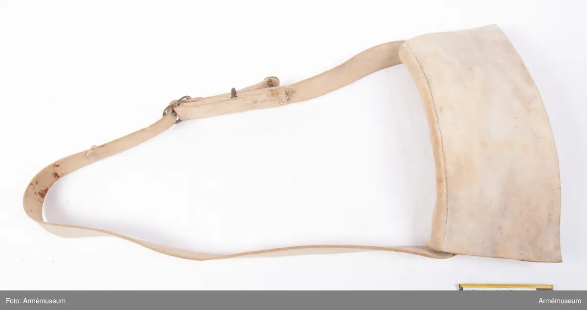 Patronväska av vitt sämskskinn med rem.
Inuti kartuchen finns en bleckplåtsinsats med rum för 12 patroner av ca 18 mm kaliber och plats för en liten oljeflaska. Under locket sitter även en extra ficka,