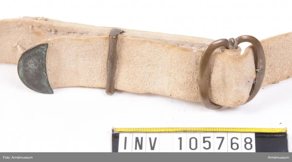 Patronväska av vitt sämskskinn med rem.
Inuti kartuchen finns en bleckplåtsinsats med rum för 12 patroner av ca 18 mm kaliber och plats för en liten oljeflaska. Under locket sitter även en extra ficka,