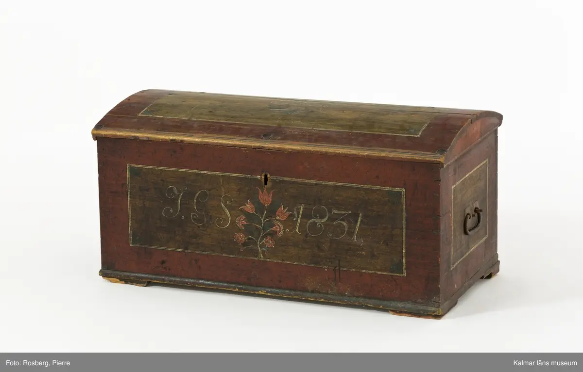 KLM 45384. Kista. Furu, järn. Kista med kupat lock och sinkade hörn. Bandgångjärn på insidan av locket och på baksidans utsida. På båda kortsidorna finns bärhandtag av smidesjärn. På fronten syns spår av en oval nyckelskylt, som nu ärborta. Lås saknas. Kistan står på fötter som är kraftigt nedslitna. Kistan är utvändigt bemålad med rödbrunt  ådringsmålat ramverk kring ekådrade fyllningar. Fronten är målad med initialerna J.G.S, årtalet 1831 i vitt, samt en blomsterslinga med sju blommor i rött. Baksidan är  enfärgad i rödbrunt. Inne i kistan finns på vänstra sidan en läddika med med ett lock målat i rödbrunt. I övrigt är kistan omålad invändigt.
