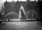 Staty (fontän) vid Mariatorget i Stockholm.
Bostadshus i bakgrunden.