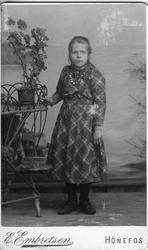 Ei jente stående ved et blomsterbord. Jenta er Gunda Kristia