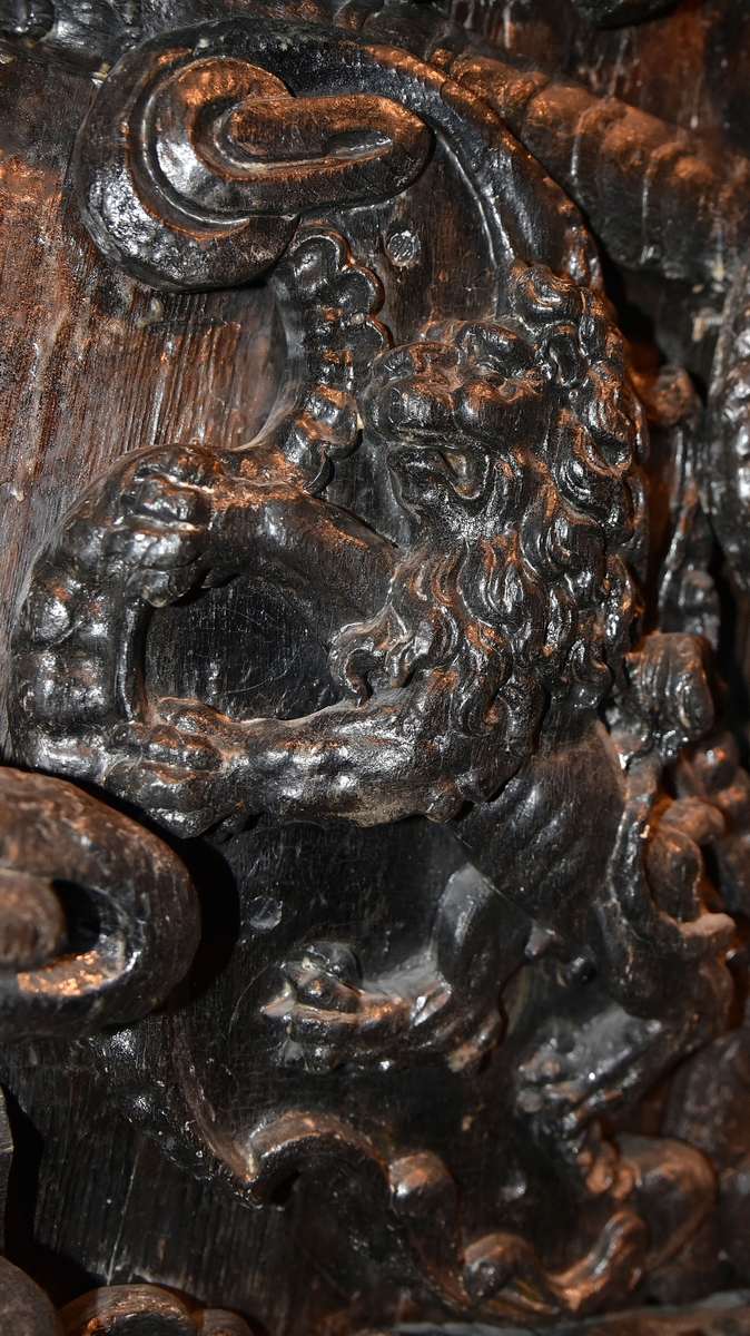 Skulpterad sköld, med upprätt, mot höger gående lejon. Lejonet är snidat i hög relief, med en heraldiskt stiliserad hållning. Sköldens kontur är rokokomässig, med kanter av varierande bredd och rik pärlbroskdekoration. Den vänstra kanten är något insvängd på mitten. Upptill avslutas skölden med en ellipsformad broskvolut. Baksidan är slät.

Text in English: Shield with upright, rightward-facing lion. The lion is carved in high relief and reproduced in perspective. It is seen in profile, and its posture is heraldically stylised. The shield has an almost rococo-like outline, with edges of varying width and rich earshell work decorations. The left-hand edge of the shield is somewhat narrowed at the middle.The top the shield is finished with an ellipse-shaped pearlwork scroll. The reverse side is smooth.