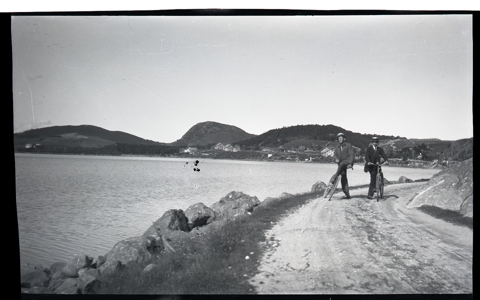 Ola Augleng og Anton Tegle (1900 - 1982) på vegen frå Ålgård som ligg i bakgrunnen. Edlandsvatnet med garden Edland til venstre over vatnet.