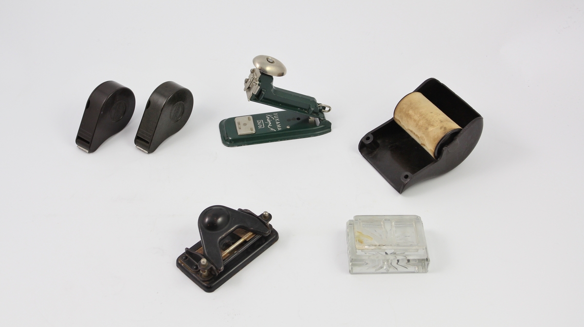 Seks kontorrekvisitter: to tapedispensere, en stiftemaskin, en hullemaskin, en papirdispenser og en frimerkedispenser.