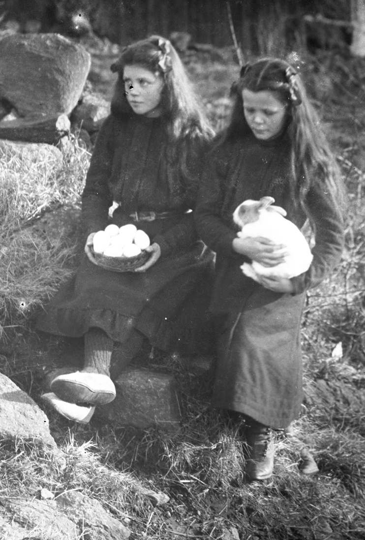 Barnporträtt. Fotografens två systrar Signe, med en kanin och Lydia med hönsägg på ett fat - symboler för påsken. 1910-tal.