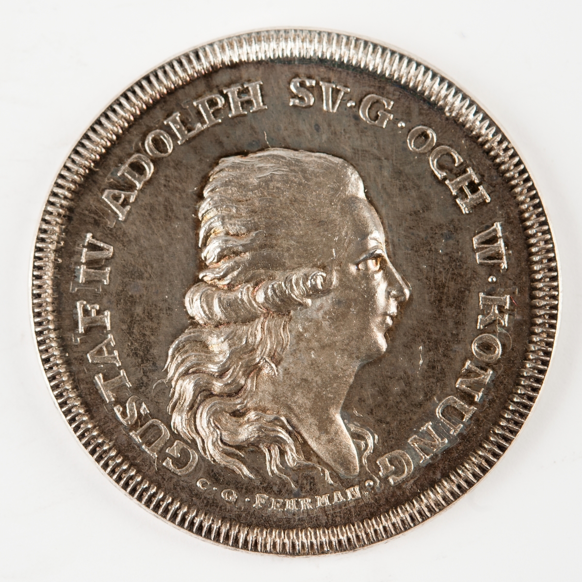 Åtsidan: Porträtt av Gustaf IV Adolf. Frånsidan: text och däröver tre kemiska tecken för krutets beståndsdelar, svavel, kol och salpeter.