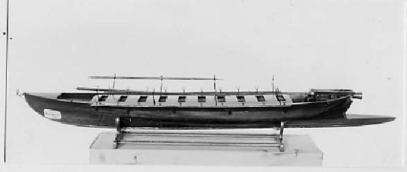 Modell. Kanonjolle av 1788 års typ. Origgad. Bordlagd på spant, kravell, med inredning och utdragen akterstäv. 10 par årtullar, 2 stycken åror. Fernissad med röd-svart reling. Däck och inredning brunmålade. 1 metallkanon. Restaurerad. Brunmålat stativ. Byggd för rodd både akteröver och föröver. Trämask. Nytt skrå 1937. 24 pundig kanon i aktern. 1 man vid åran.