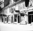 Skioptikonbild med motiv från gata i Helsingborg. Kemisk tvättanstalt, färgeri. Norra Storgatan 9 som efter en restaurering på 1920-talet går under namnet Gamlegård.
Bilden har förvarats i kartong märkt: Helsingborg 8. 1908