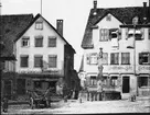 Skioptikonbild med motiv av fontän på torg vid bokbinderi i Besigheim.
Bilden har förvarats i kartong märkt: Resan 1907. Besigheim 8. 29