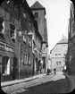 Skioptikonbild med motiv av man på cykel vid hästskjuts, på gata i Erfurt.
Bilden har förvarats i kartong märkt: Resan 1907. Erfurt 10. 14