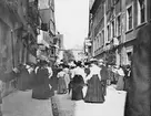 Skioptikonbild med motiv av människor på Hirchbrunnstrasse i Heilbronn.
Bilden har förvarats i kartong märkt: Resan 1907. Heilbronn 6. Stuttgart 1. Berlin 2.. Text på bild: 