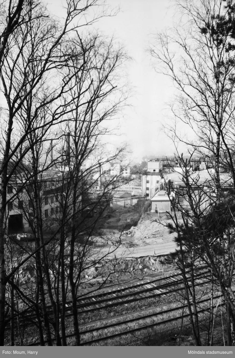 Vy över Boråsbanans järnväg på vägarbete i backen "Kråkan" (Kvarnbygatan i Mölndal), år 1984. Till vänser ses "Strumpan" (Kvarnbygatan 10-14) och till höger fabriksbyggnader tillhörande Soab.

Fotografi taget av Harry Moum, HUM, Mölndals-Posten, vecka 12, år 1984.