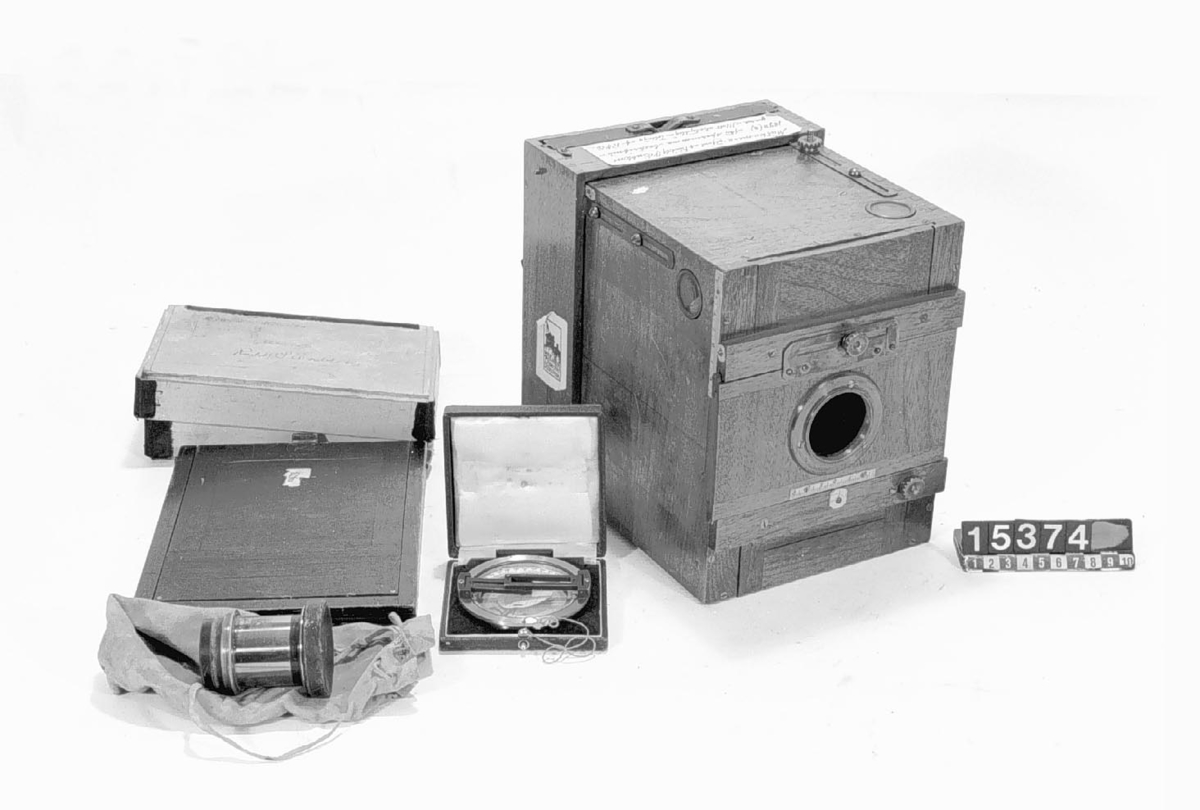 Utrustning för fotogrammetri som tillhört ingenjör R. S. Enblom, Djursholm. Den var avsedd för uppmätning av enskilda byggnader och större byggnadskomplex. Objektivet kommer från det engelska företaget Perken, Son & Rayment i London och är av typen Rapid Rectilinear med 1:8 som största bländare. Till objektivet hör lock samt sex insticksbländare i läderfodral. Negativformatet är 9x12 cm och kameran har inbyggda vattenpass. Ingenjör Engblom har förbättrat utrustningen med bl.a. påmonterade mätskalor. I utrustningen ingår även dubbelkassetter 13x18 cm och en handhållen kompass med diopter. 
Tillbehör: Kamera, kompass med diopter (i fodral), 6 st. insticksbländare (i fodral), 2 st. stödhakar, foto och 2 st. ritningar för demonstration, objektic (Perkenson-Rayment Hatton Garden rapid rectilinear 7 x 5) med lock, visirskiva, pappask samt dubbelkassett 13 x 18 cm, väska.