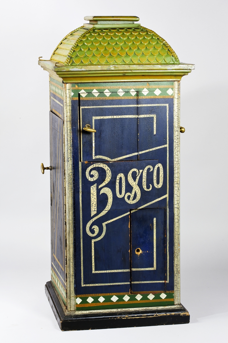 Fotoautomat "Bosco" för tillverkning av ferrotypier. Penningautomat för självfotografering.  Den fungerade på så sätt att det ljuskänsliga skiktet placerats i en profilerad plåtbricka som på samma gång var framkallningsskål och sedan ram för fotografiet. I automaten exponerades bilden i lodrätt läge och framkallades sedan med vätskor som portionerades ur behållare. Efter tre minuter var ferrotypen klar och matades ut ur apparaten. Den behövde torka ytterligare och fick enligt anvisningarna inte utsättas för starkt ljus förrän den var torr. Bilden mätte 60x83 mm och levererades i ett etui av papper. Plåtbrickan hade påtryck av reklam och information på baksida och kanter.
Tillbehör: Sockel med 2 st. metallådor för plåtar, 10 st. plåtar ("W.H.C Bernitt Original Bosco Platte Hamburg 23 ...), överdel med kamera, mekanism, mekanism för framkallning m.m. nyckel till verket.