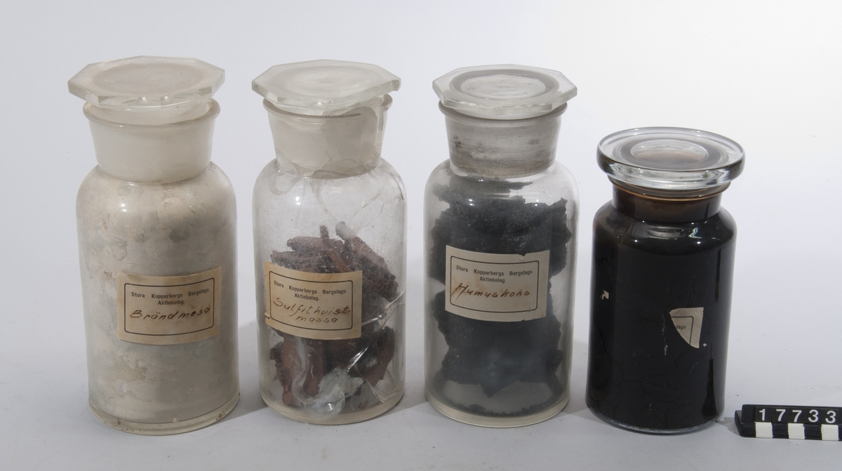 Prov på olika slag av biprodukter från sulfitmassefabrikation. I flaskor: sulfitkvistmassa, bränd, mesa, humuskoks, såpa. Humuskoks. H:220, D:100, Vikt:1,32. Svart. Sulfitkvistmassa. H:220, D:105, Vikt:1,21. Brun. I bitar. ? - H:180. D:95, Vikt:1,33. Svart,etiketten borta. Brändmesa. H:230, D:100. Vikt:1,9. Vitgrå.