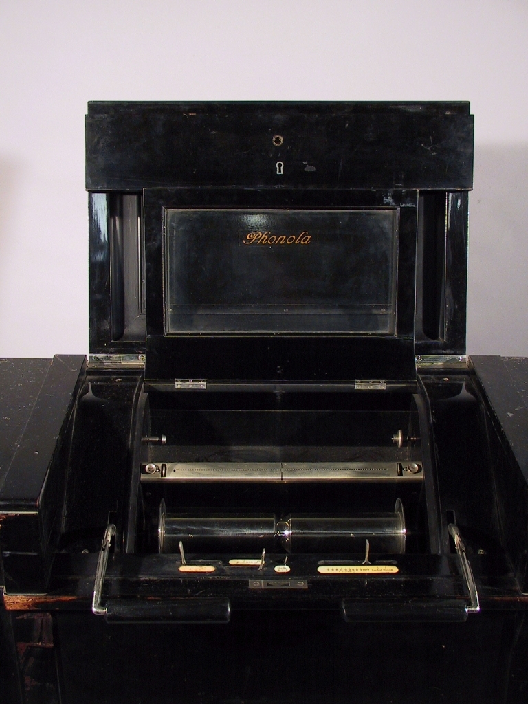 Pianotillsats för automatisk spelning på pianoklaviatur medelst perforerade notrullar av papper för pneumatisk verkan. Modell 1919. Märkt: Piano nr 14227, apparat nr 19422, verk nr 82947.
Tillbehör: Stol, svartlackerad.