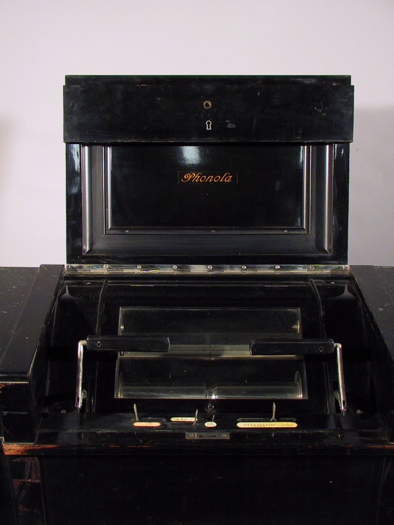 Pianotillsats för automatisk spelning på pianoklaviatur medelst perforerade notrullar av papper för pneumatisk verkan. Modell 1919. Märkt: Piano nr 14227, apparat nr 19422, verk nr 82947.
Tillbehör: Stol, svartlackerad.