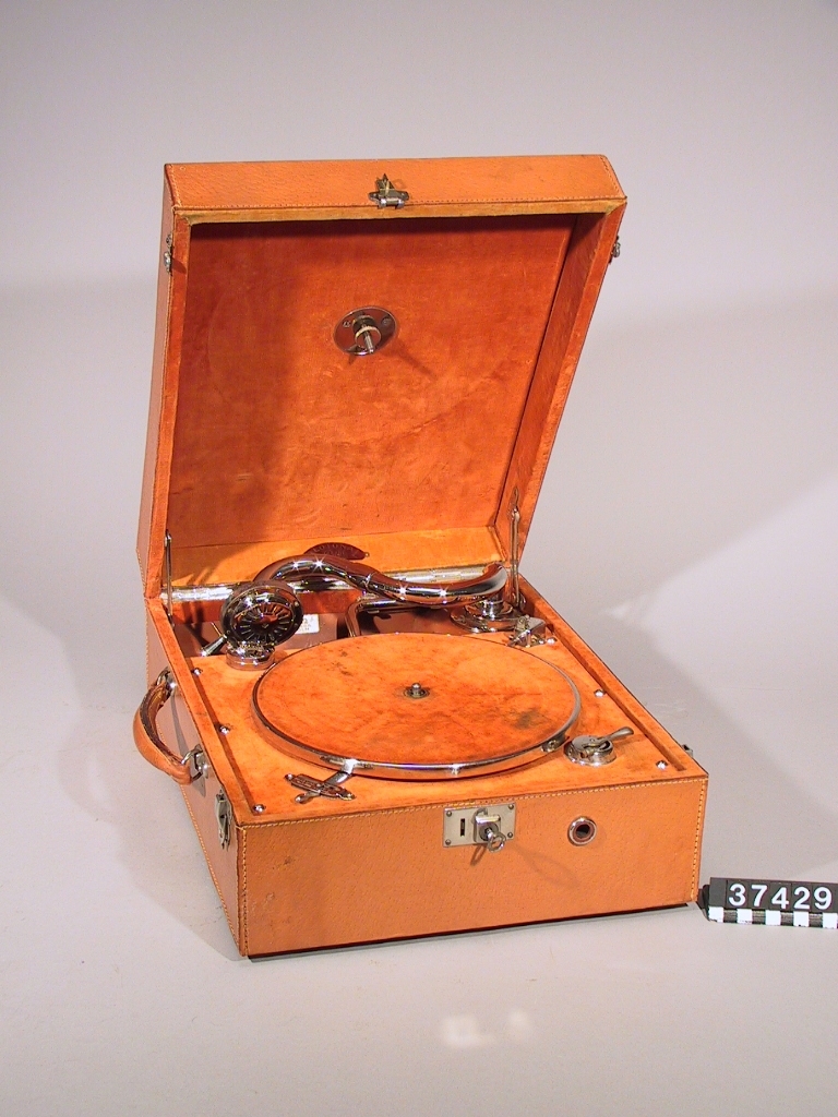 Resegrammofon, med fjäderverk, stiftdosa och hastighetsregulator. Läderklädd väska och förnicklade metalldelar.
Tillbehör: 2 vevar och nyckel.