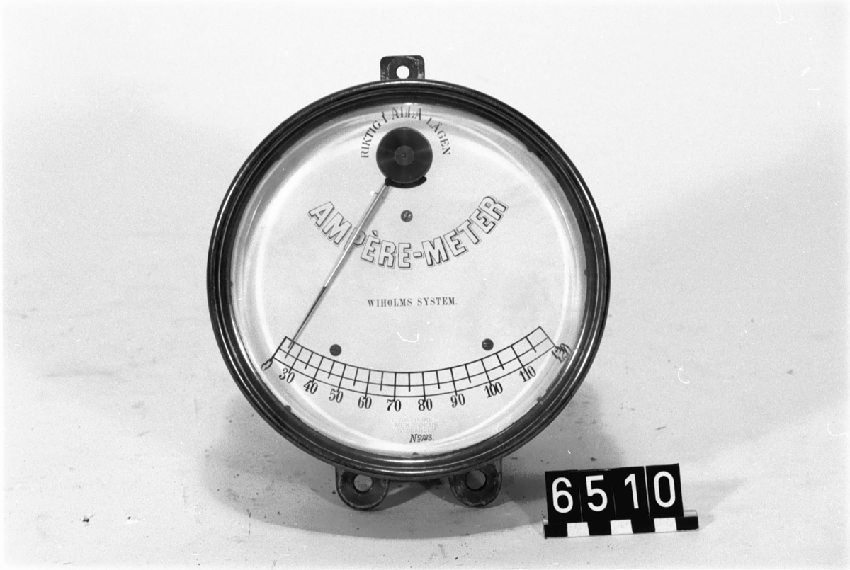 Enligt Wiholms system. Text på visartavlan: "Riktig i alla lägen, Ampére-meter, Wiholms system, 0-120". Inpressat: "Aktiebolaget, Mekanikus, Stockholm" "N:o 183"