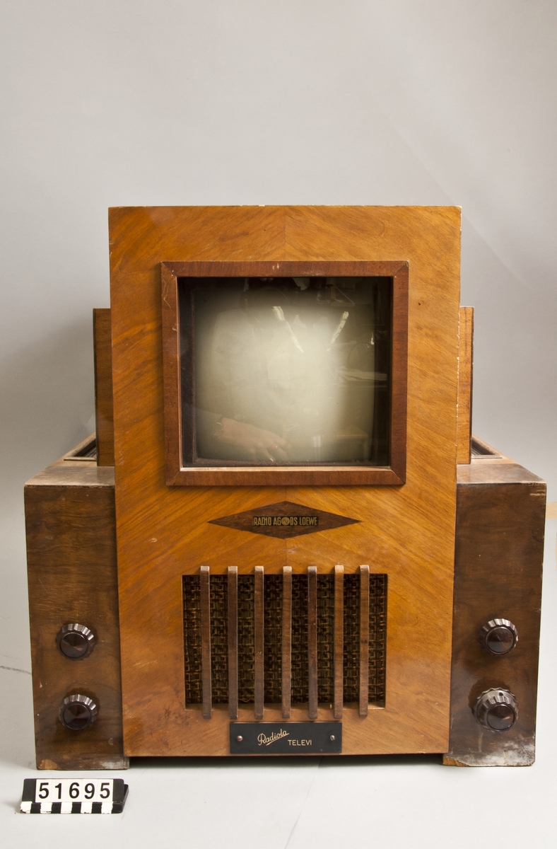 Tv-apparat i björkfaner. 25 cm bildrör med 19x16 cm bildyta. UKW-mottagning. 180/240 linjers upplösning 50 bilder/sek. Märkt: Loewe-erst-tv-05