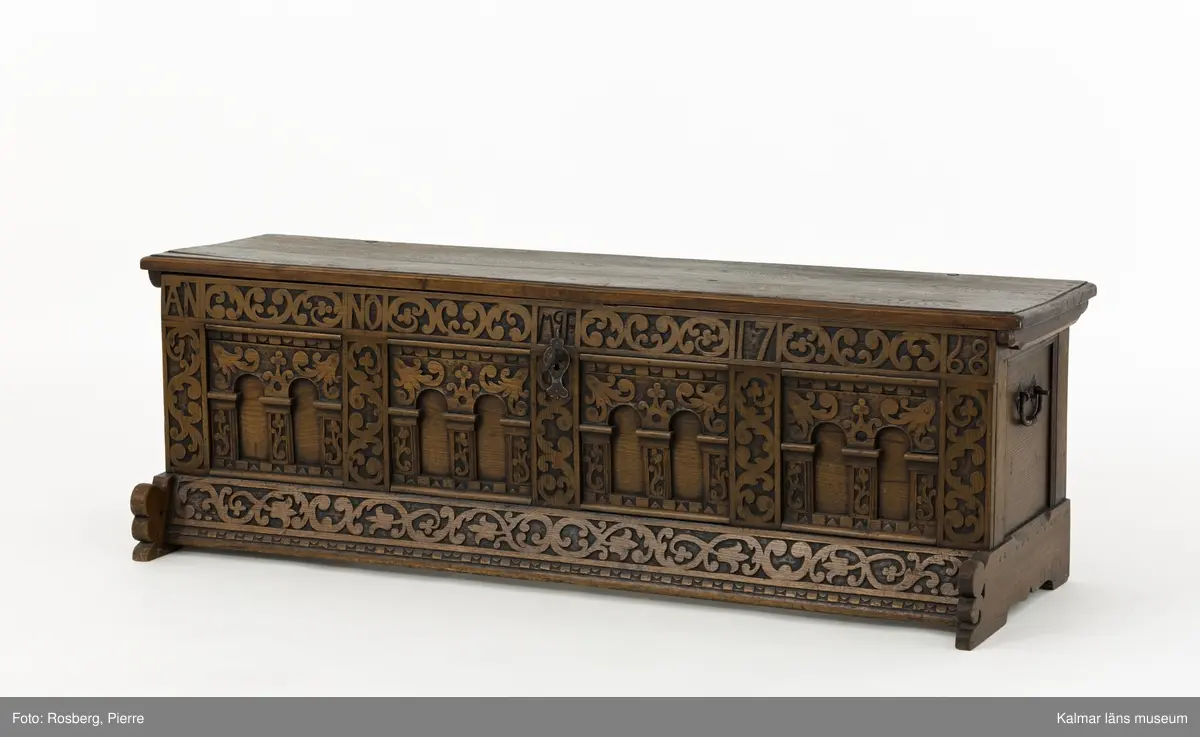 KLM 45387. Ek, järn. Långsmal kista eller bänk i mörk ek med platt lock och rikt utskuren reliefdekor i renässansstil på kistans front. Texten "Anno 1768" och initialerna "MGF" är snidade på fronten. Bandgångjärn på lockets insida och på baksidans utsida. På båda kortsidorna finns smidda bärhandtag av järn. På kistans front finns en nyckelskylt och inne i kistan ett lås av smide. Inne i kistan finns en läddika på den vänstra sida. På frontstyckets ovansida är följande text inristad: "17 IF:MAGRET FREIN:71".