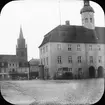 Skioptikonbild med motiv av Rådhuset vid St. Marienkirche i Neubrandenburg.
Bilden har förvarats i kartong märkt: Resan 1912. Neubrandenburg. Text på bild: 