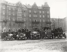 Elever vid Eric Lundviks körskola, samlade kring fem automobiler på Karlaplan, omkring 1915-1920.