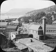 Skioptikonbild. Peekskill omkring 1890. Vy åt nott mot Water Street med Annsville Creek rakt fram. Hudson River till väst. I buggnaden med tornet nere till höger hade brandkåren sina vagnar och i det stora tornet torkade man hästarna.