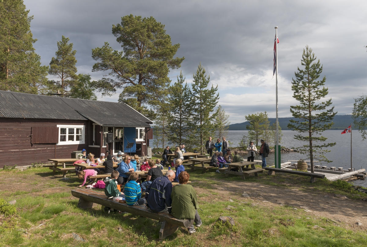 Fotografiet er tatt på sletta foran huset museet bruker som kafé- og resepsjonslokale. Blant publikum sitter blant annet elever og personale fra Osen oppvekstsenter, med flere.