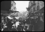 Skioptikonbild från institutionen för fotografi vid Kungliga Tekniska Högskolan. Bilden är troligen tagen av John Hertzberg under en resa i Europa. Hertzberg blev docent i fotografi 1921vid Kungliga Tekniska Högskolan i Stockholm. Gatuliv.