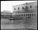 Skioptikonbild från institutionen för fotografi vid Kungliga Tekniska Högskolan Motiv från Venedig. Gondol med gondoljär  på en av kanalerna. Till höger i bild Doge palatset (Palazzo Ducale). Bilden är troligen tagen av John Hertzberg under en resa i Europa.