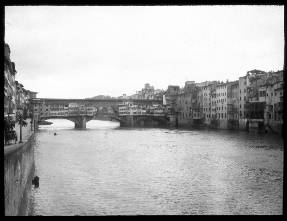 Skioptikonbild från institutionen för fotografi vid Kungliga Tekniska Högskolan. Motiv föreställande bron Ponte Vecchio i Florens. Bron stod färdig år 1345. Bilden är troligen tagen av John Hertzberg under en resa i Europa.
