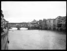 Skioptikonbild från institutionen för fotografi vid Kungliga Tekniska Högskolan. Motiv föreställande bron Ponte Vecchio i Florens. Bron stod färdig år 1345. Bilden är troligen tagen av John Hertzberg under en resa i Europa.