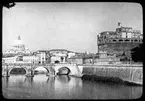 Skioptikonbild från institutionen för fotografi vid Kungliga Tekniska Högskolan. Motiv föreställande vy från Rom, Italien. Tibern med Vatikanen (Peterskyrkan) till vänster i bild och Castel Sant' Angelo till höger.Bilden är troligen tagen av John Hertzberg under en resa i Europa.