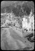 Skioptikonbild från institutionen för fotografi vid Kungliga Tekniska Högskolan. Motiv föresällande stadsbebyggelse vid strand, sannolikt i  södra Italien. Bilden är troligen tagen av John Hertzberg under en resa i Europa..