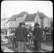 Skioptikonbild från institutionen för fotografi vid Kungliga Tekniska Högskolan. Motiv föreställande torghandel sannolikt i Bergen, Norge. Bilden är troligen tagen av John Hertzberg under en resa i Europa.