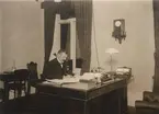 Fotografi ur album tillhörande Ester Holmberg, anställd vid Telegrafstyrelsens statistikavdelning 1902. Fotografierna troligen tagna 1907. Gd Rydin vid skrivbordet.