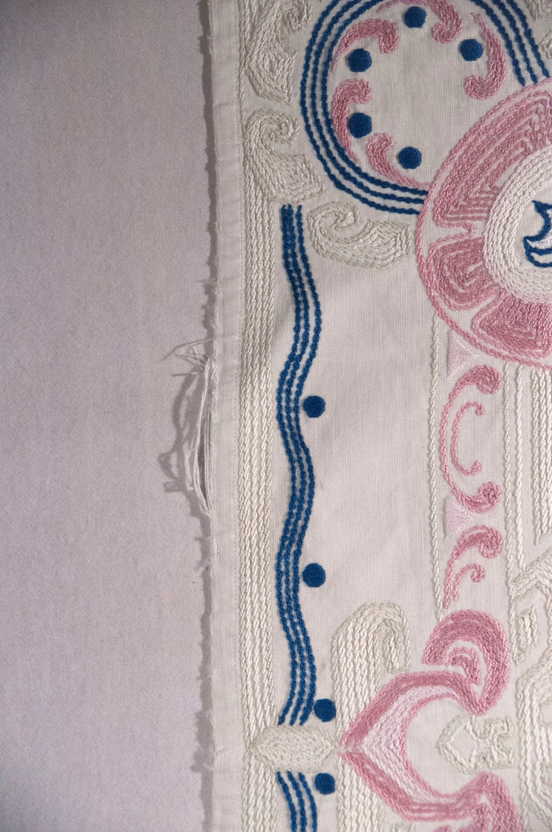 Bomullslerret, falda og brodert med attersting.