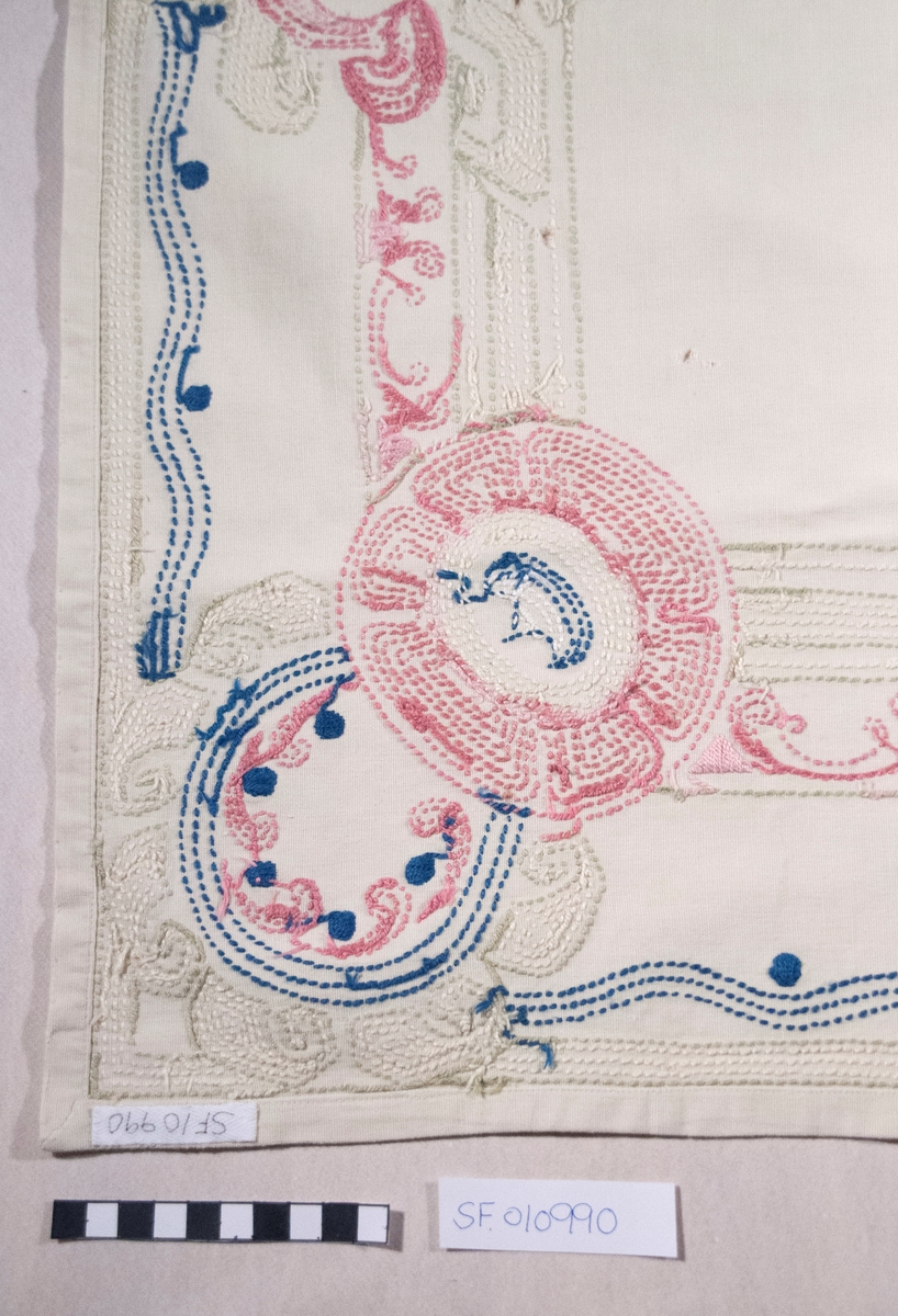Bomullslerret, falda og brodert med attersting.